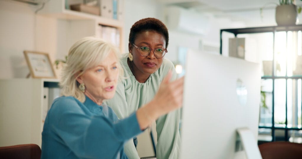 Business woman, office team and computer with meeting and blog post for digital journalist at creative agency. Working, employee and desk with planning and company website update with discussion