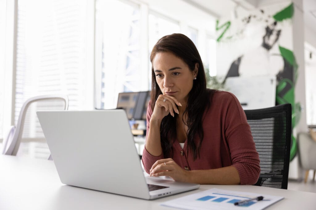 Thoughtful serious business project manager working at laptop