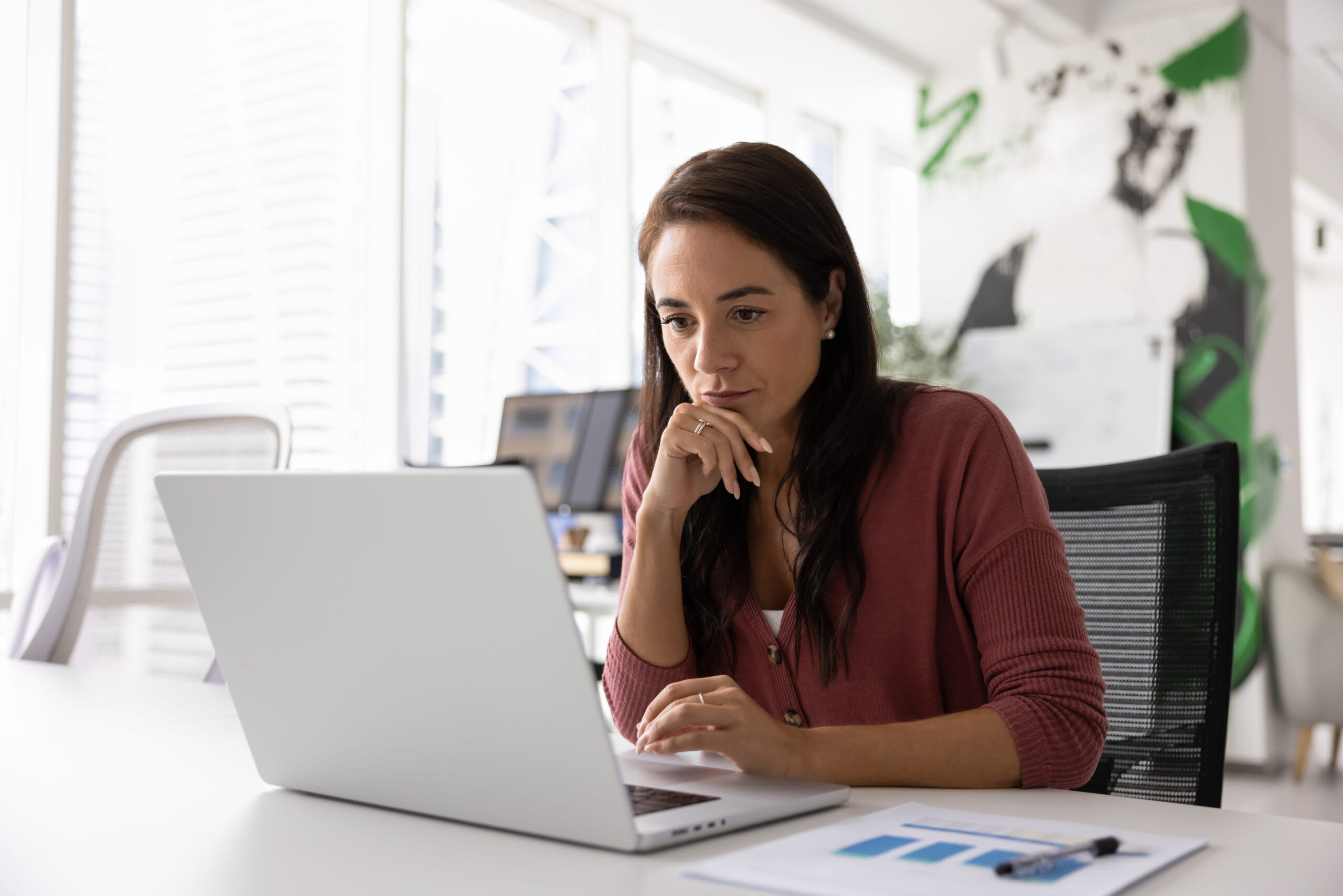 Thoughtful serious business project manager working at laptop