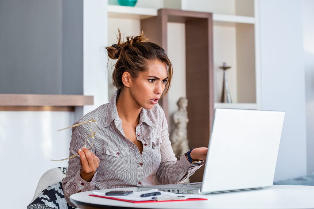 Young businesswoman misunderstanding her laptop at her desk in office. woman working with laptop at home or modern office. Serious, confused, or frustrated expression.