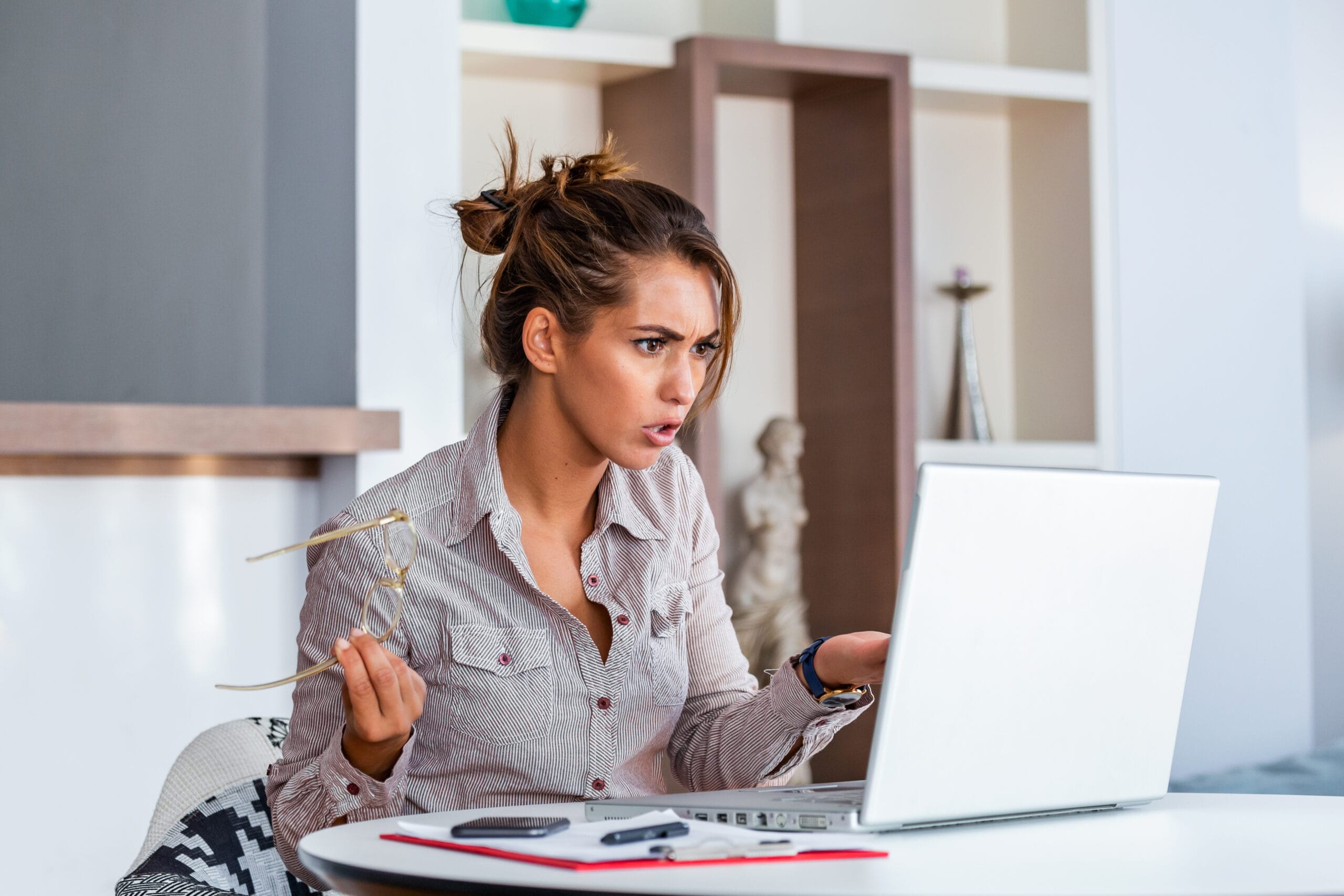 Young businesswoman misunderstanding her laptop at her desk in office. woman working with laptop at home or modern office. Serious, confused, or frustrated expression.