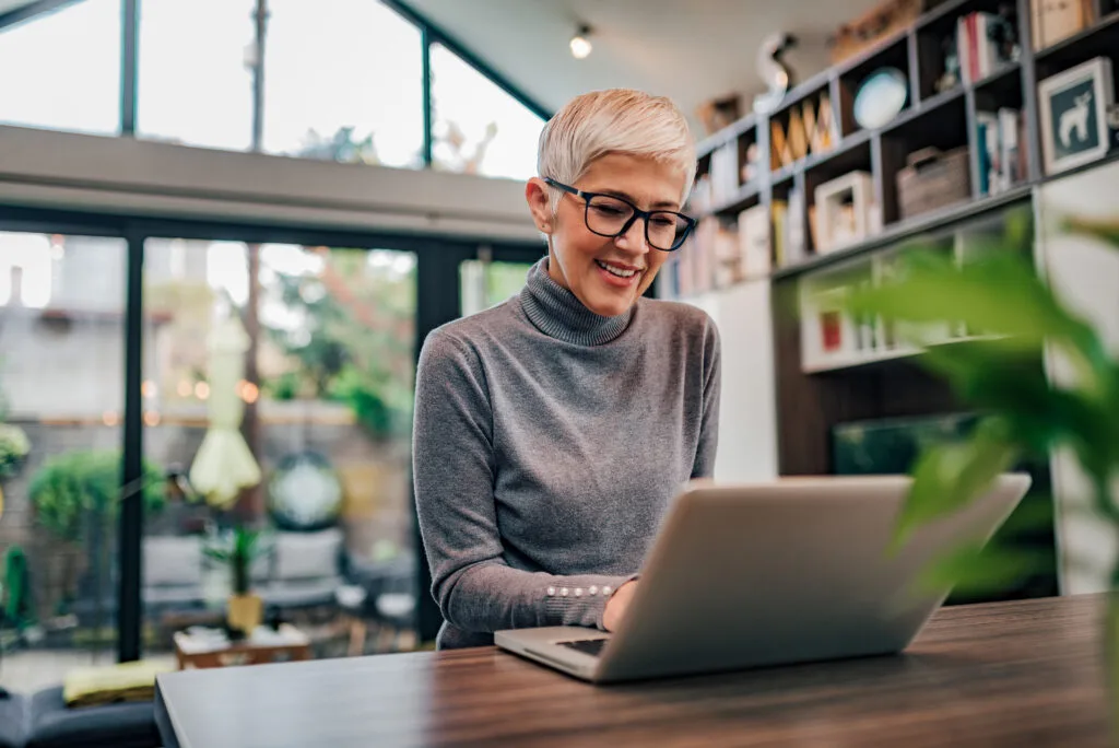 Portrait of a cheerful mature businesswoman working on laptop at