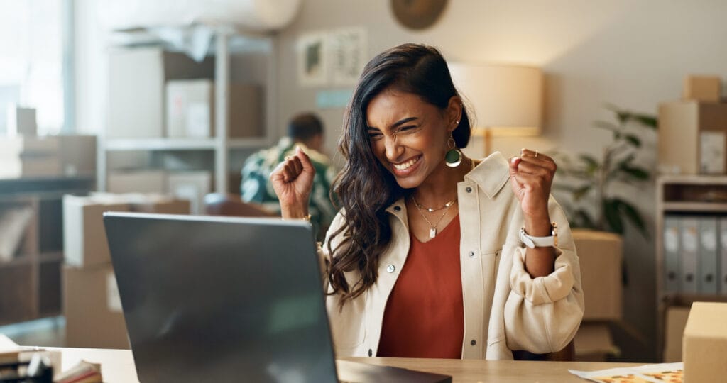 Business woman, winner and boxes or computer for logistics celebration, startup success and e commerce profit. Entrepreneur, seller or Indian supplier with package, courier news or winning on laptop